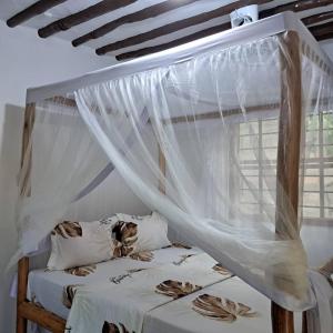 una camera con letto a baldacchino e tende bianche di JozaniBiospherevillage a Jozani