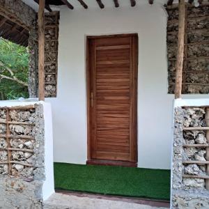 una porta di legno sul lato di una casa bianca di JozaniBiospherevillage a Jozani
