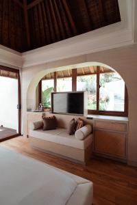 a bedroom with a couch in front of a large window at Poco Poco villas by Aayan in Jimbaran