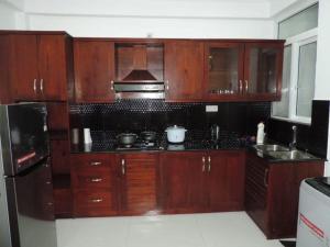 a kitchen with wooden cabinets and a stove top oven at SEA BREEZE HOLIDAYS HOME in Colombo