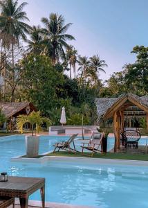 een zwembad in een resort met stoelen en een tafel bij El Nido Moringa Resort in El Nido