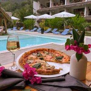 een pizza en een glas wijn op een tafel bij het zwembad bij El Nido Moringa Resort in El Nido