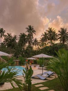 a resort swimming pool with umbrellas and palm trees at El Nido Moringa Resort in El Nido