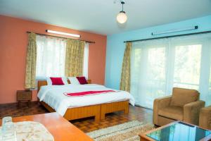 ein Schlafzimmer mit einem Bett, einem Sofa und einem Stuhl in der Unterkunft Holiday Home near Swayambhunath Stupa in Kathmandu