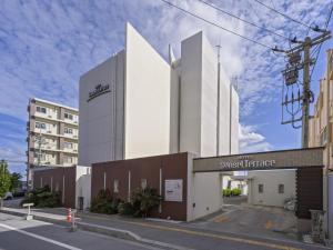 a white building with a sign on a street at Hotel Sunset Terrace in Chatan