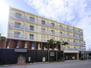 un grande edificio con palme di fronte di Hotel Sunset Terrace a Chatan