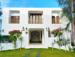 una casa blanca con palmeras delante en Stelia Beach Resort en Tuy Hoa