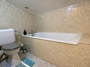 a bathroom with a white tub and a toilet at Maison de Charme 95m2 à Saint-Denis PLEYEL, 4 Chambres, Terrasse, Calme, Proche Paris et Stade de France in Saint-Denis
