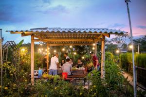 un groupe de personnes assises à une table sous un kiosque dans l'établissement Bungalow - Farmstay Hoa Rừng U Minh, à Cà Mau