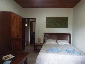 een slaapkamer met een bed en een tafel en een schilderij bij Casa Malibu in Ilha de Boipeba