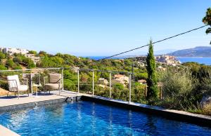 een zwembad met 2 stoelen en uitzicht op de oceaan bij Villa Sottu in Calvi