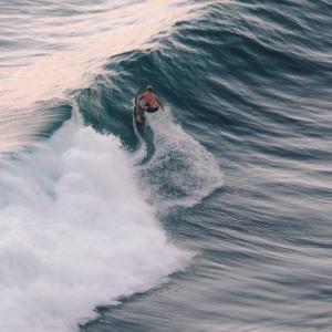 a man riding a wave on a surfboard in the ocean at Kala Surf Camp in Uluwatu