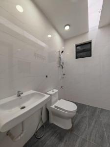 La salle de bains blanche est pourvue de toilettes et d'un lavabo. dans l'établissement VegeGarden Cozy Home @Ipoh Town Center, à Ipoh