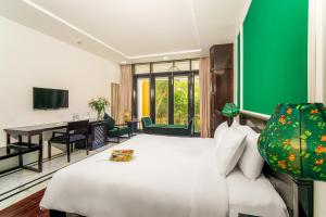 1 dormitorio con 1 cama blanca grande y escritorio en Thanh Binh Riverside Hoi An, en Hoi An