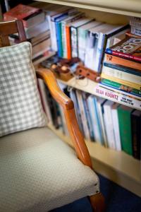 a chair in front of a book shelf with books at The Beach House At Bayside in Albany