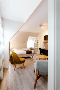a bedroom with two beds and a living room at Logis Hotel Le Relais De La Poste Restaurant Le Fil du Temps in Thury-Harcourt
