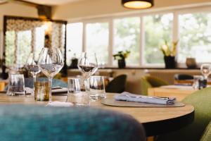 una mesa en un restaurante con copas de vino. en Logis Hotel Le Relais De La Poste Restaurant Le Fil du Temps, en Thury-Harcourt