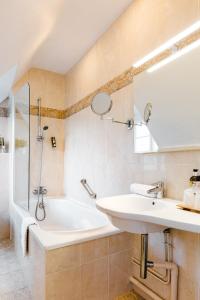 a bathroom with a sink and a bath tub at Logis Hotel Le Relais De La Poste Restaurant Le Fil du Temps in Thury-Harcourt