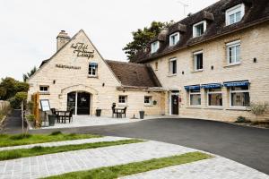 um grande edifício de tijolos com mesas em frente em Logis Hotel Le Relais De La Poste Restaurant Le Fil du Temps em Thury-Harcourt