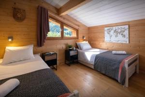 a bedroom with two beds in a wooden cabin at Chalet Paravis - OVO Network in La Clusaz