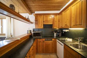 a kitchen with wooden cabinets and a sink at Chasa Tanter Vias - Capricorn in Scuol