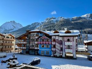 un edificio nella neve con montagne sullo sfondo di Cesa Planber Apartments Mountain View BIKE FRIENDLY a Canazei