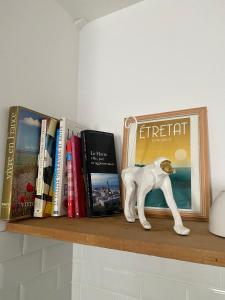 een plank met boeken en een hondenbeeld erop bij L’appart Duplex Bis in Le Havre
