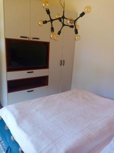 a bedroom with a tv and a chandelier at Villa Erdődy Resort in Oravská Lesná