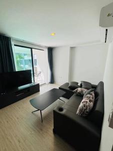 a living room with a black couch and a flat screen tv at Centrio Condo CENTRAL PHUKET c419 in Ban Rangeng