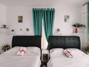 2 camas en una habitación con cortinas verdes en Inap Idaman 5 With 2 Queen Bed In Kubang Kerian, en Kota Bharu