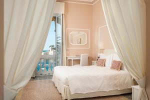 a bedroom with a white bed and a balcony at Hotel Helvetia in Sestri Levante