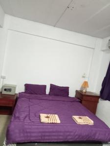 a bedroom with a purple bed with two towels on it at Chai Ben guesthouse in Jomtien Beach