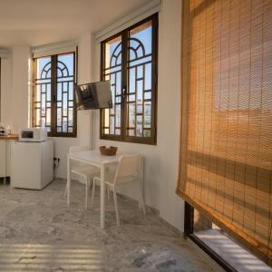 uma sala de jantar com uma mesa branca, cadeiras e janelas em Conjunto de APARTAMENTOS ANTIGUO PALACIO HOTEL PARIS em Huelva