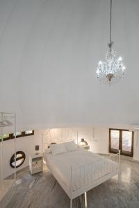 a white bedroom with a large bed and a chandelier at Conjunto de APARTAMENTOS ANTIGUO PALACIO HOTEL PARIS in Huelva
