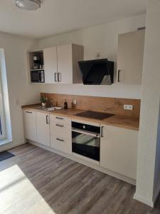 a kitchen with white cabinets and a tv on the wall at Große Pause - Moderne Ferienwohnung nahe Steinhude in Hagenburg