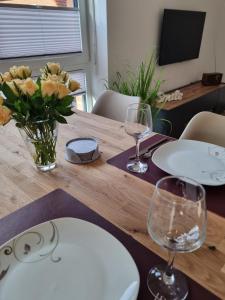 a wooden table with two glasses and a vase of flowers at Große Pause - Moderne Ferienwohnung nahe Steinhude in Hagenburg