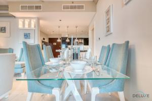 a dining room with a glass table and blue chairs at Calm 3BR in The Signature Downtown by Deluxe Holiday Homes in Dubai