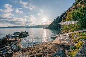 una spiaggia con ombrellone e sedie accanto all'acqua di Villa Escalina with private beach and A/C a Marciana Marina