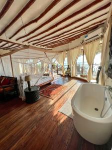 a bathroom with a bath tub in a room with wooden floors at Zi Villa Main House in Matemwe