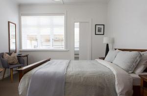 ニュープリマスにあるMichelia Figo Cottageの白いベッドルーム(ベッド1台、窓付)
