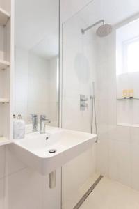 uma casa de banho branca com um lavatório e um chuveiro em Peaceful and Quiet 1BR Cottage in Camberwell em Londres