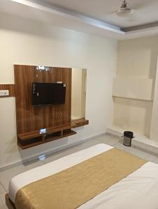 a bedroom with a bed and a flat screen tv at Hotel Lake View AC room in Vadodara