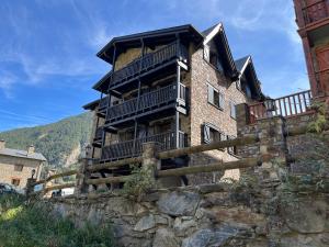 ein großes Backsteingebäude mit Balkonen an einer Steinmauer in der Unterkunft Cases de Canillo-Casa Sant Serni in Canillo