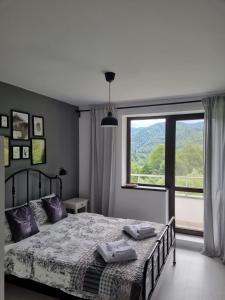 a bedroom with a bed and a large window at HCT Sinaia Apartment in Sinaia
