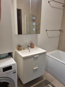 a white bathroom with a sink and a washing machine at HCT Sinaia Apartment in Sinaia