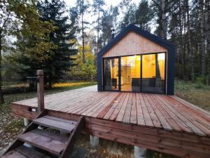 a tiny house on a wooden deck with a bench at Ramybės parkas 