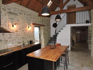 una cocina con una mesa de madera y una escalera en Gîte de la Fontaine - GOLF - AVEYRON, en Lugan