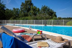 a swimming pool with a table and chairs next to a swimming pool at Camping du Lac de Saint-Pardoux in Saint-Pardoux
