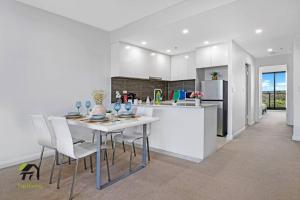 a kitchen with a white table and chairs and a refrigerator at Entire 3 Bedroom in Bankstown in Bankstown