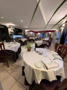 uma sala de jantar com mesas e toalhas de mesa brancas em Hôtel Bien Être La Glycine em Bénouville